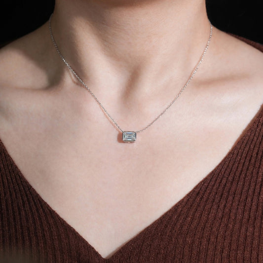 Woman wearing the Emerald Cut bezel-set moissanite pendant on a fine 925 silver chain