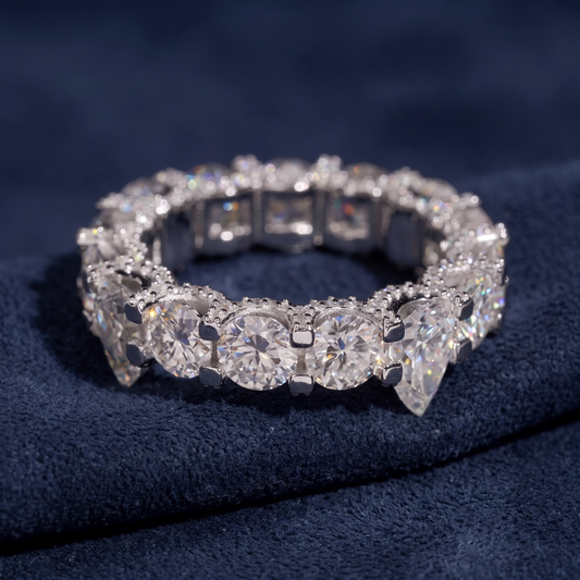 Prong-set pear and round moissanite eternity band in sterling silver on navy suede