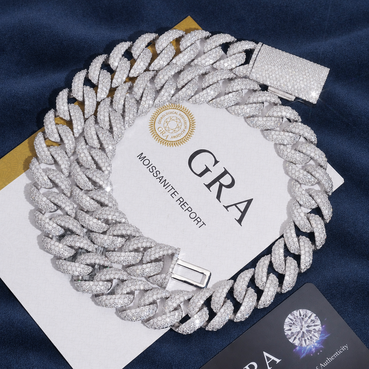 18mm Miami Cuban Chain in 925 silver coiled on navy suede beside its GRA moissanite report
