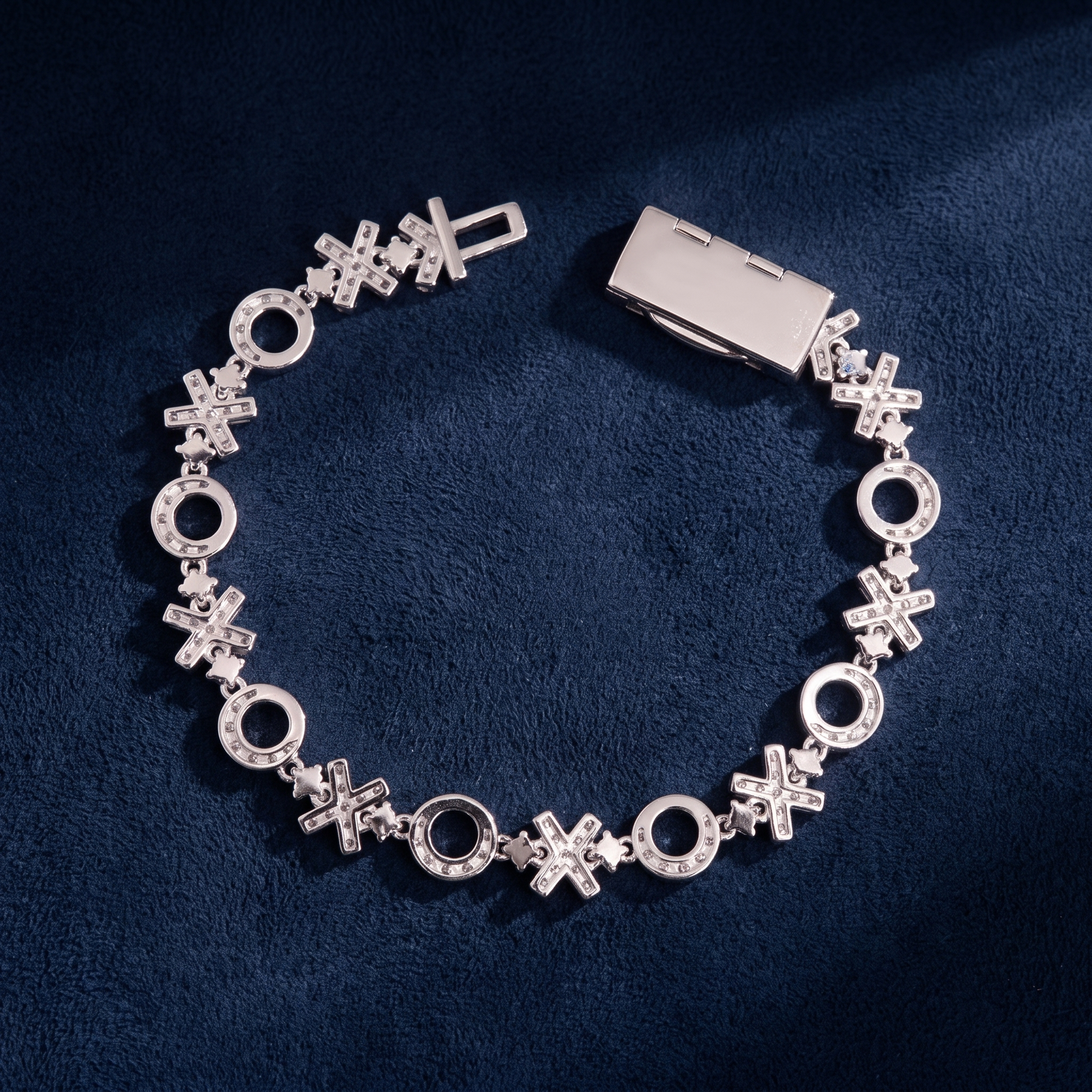XOXO Link Bracelet circular flat-lay on dark navy suede